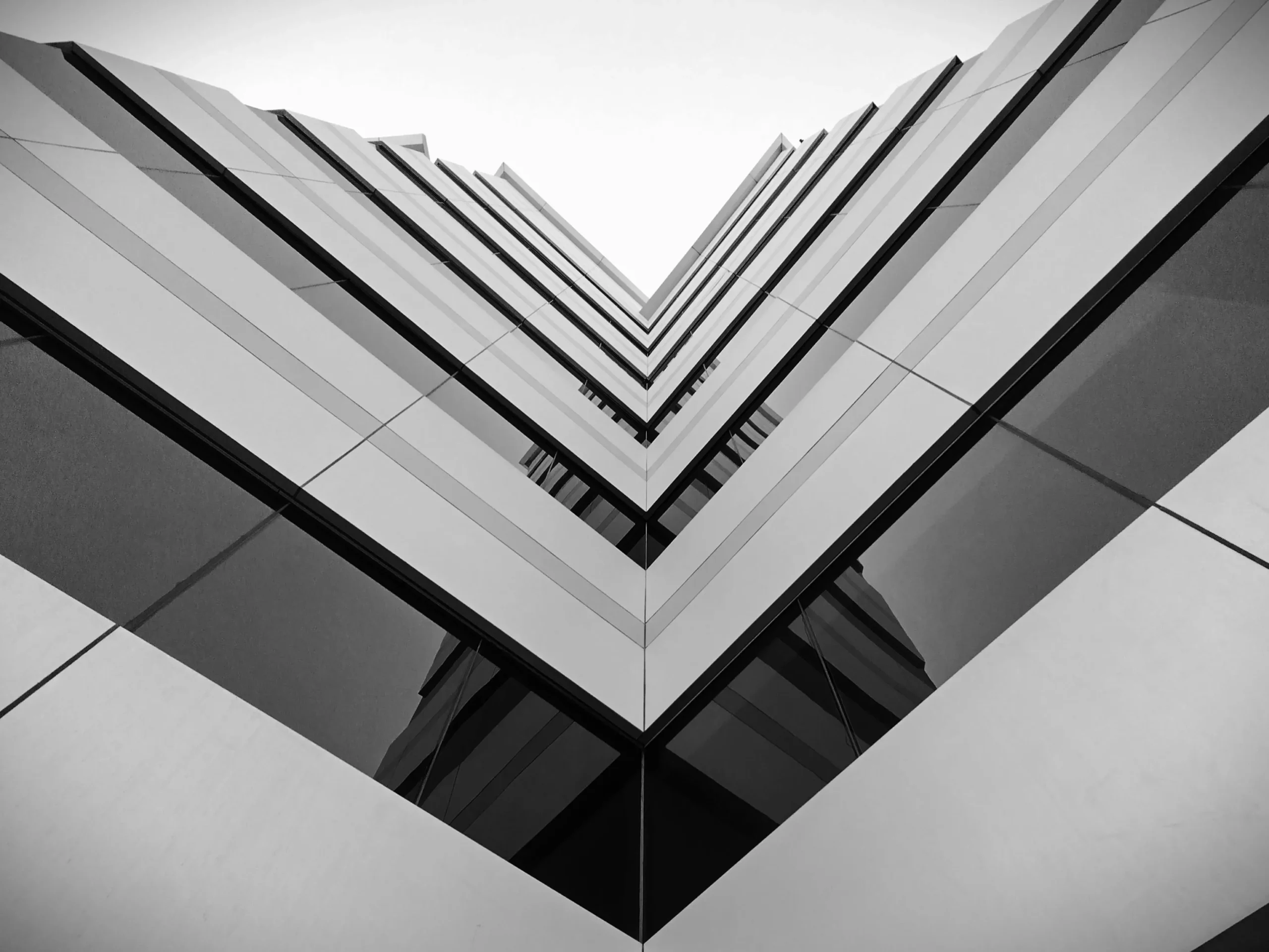 Somos expertos en Tasaci&oacute;n de inmuebles como el de la fotograf&iacute;a art&iacute;stica de la esquina interior de un edificio que muestra cristaleras. Blanco y negro.